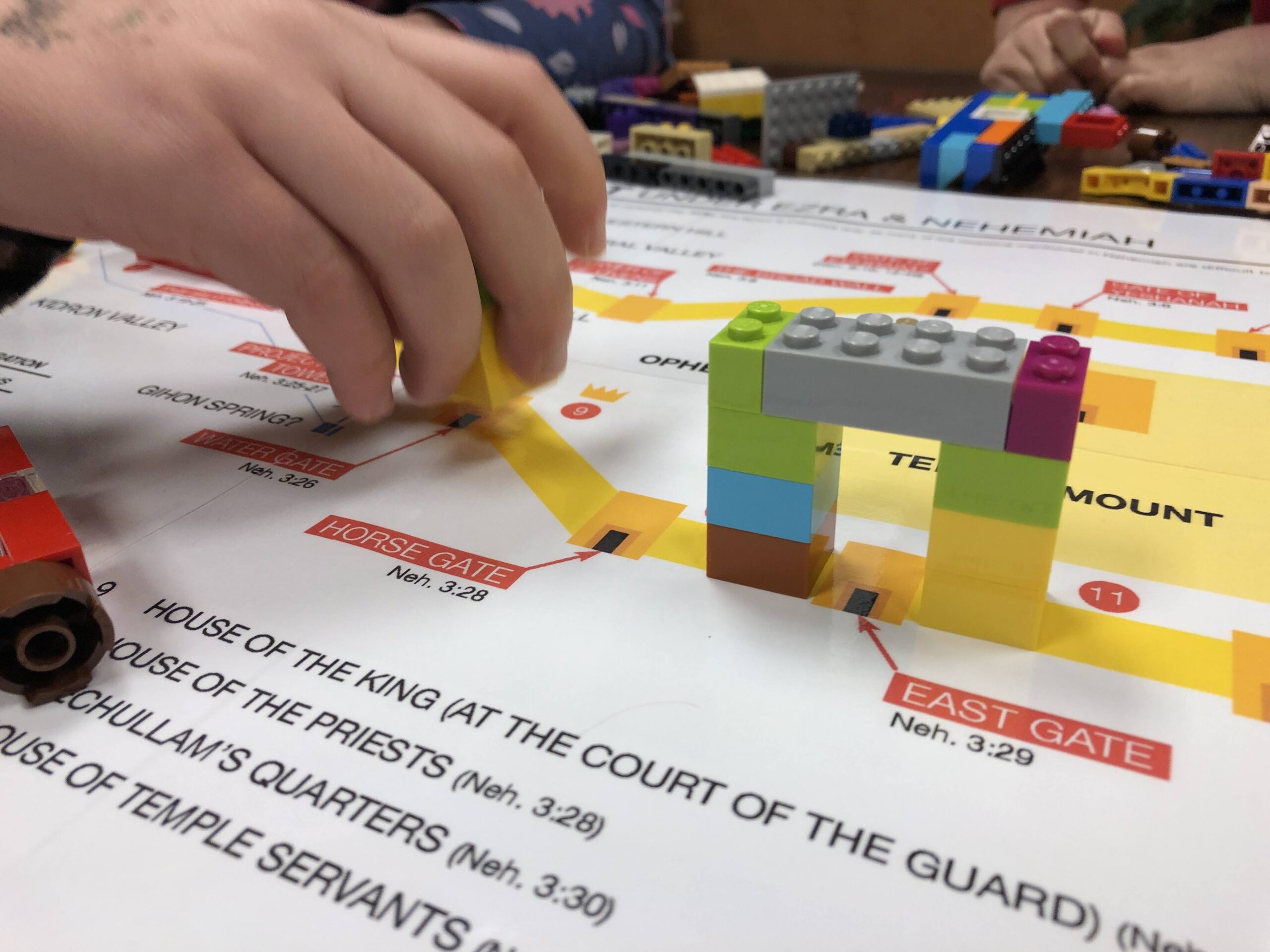 Photo of child's hand placing LEGO bricks on an annotated map.